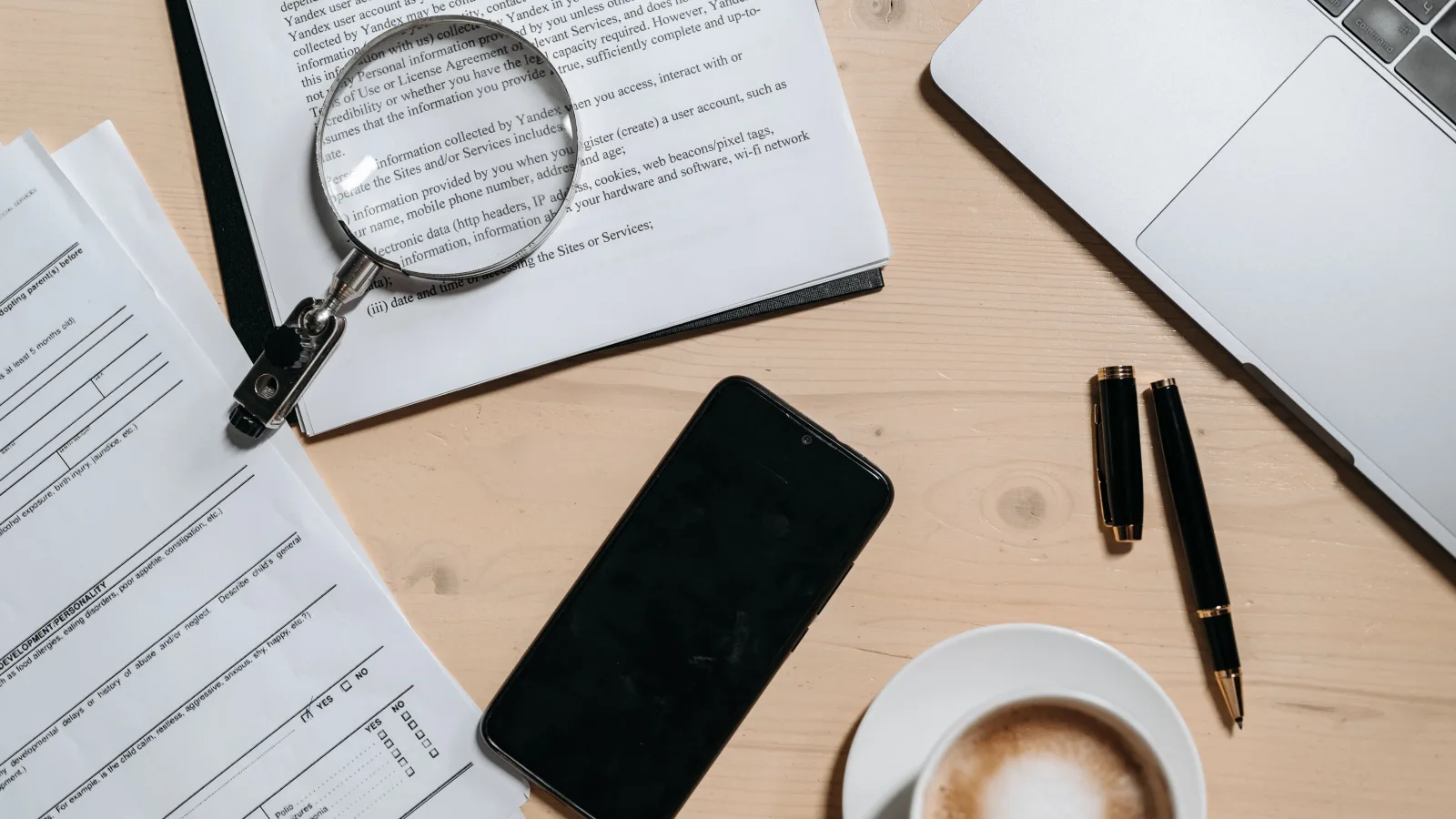 Documents, laptop and magnifying glass used for public-source review