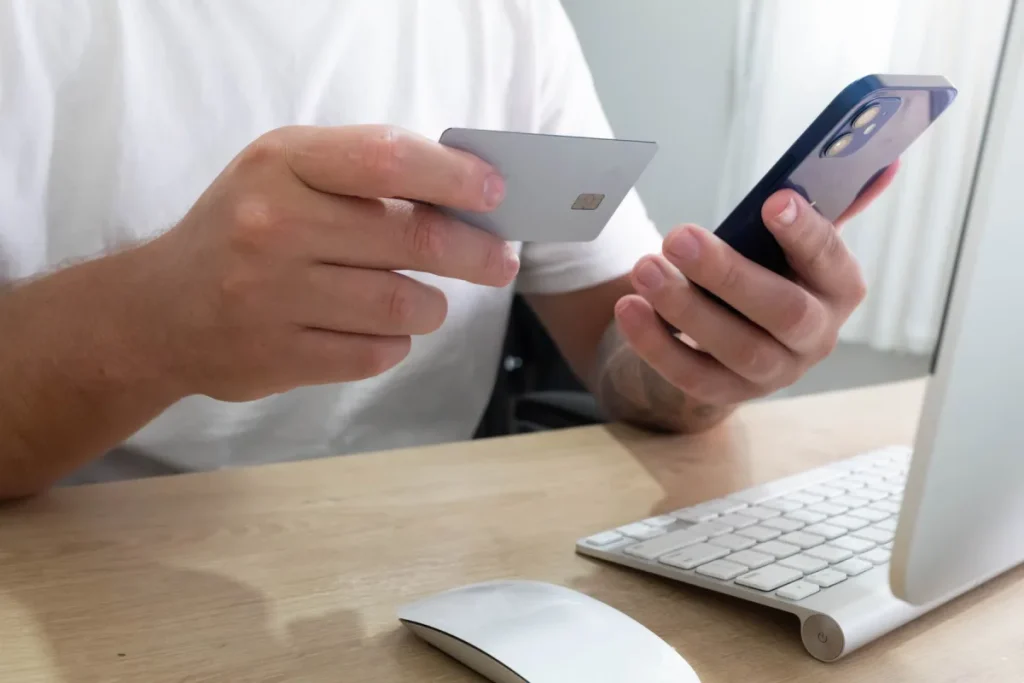 Person reviewing a smartphone and payment card before an online transaction