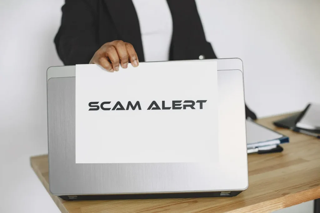 Scam warning held above a laptop during an online safety check